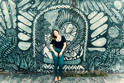 Portrait of woman standing against graffiti wall