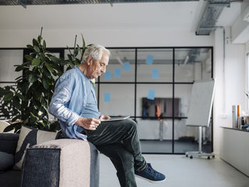 Businessman using digital tablet while sitting on sofa at office