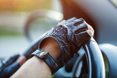 The driver's hands in leather gloves driving a moving car. woman holding