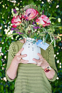 Midsection of woman holding pink flowers