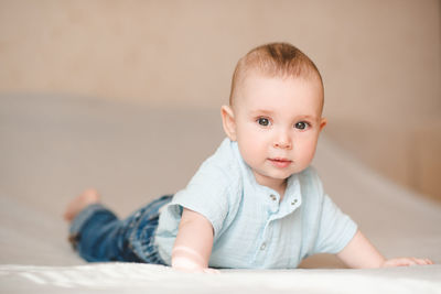 Portrait of cute baby boy lying on bed at home