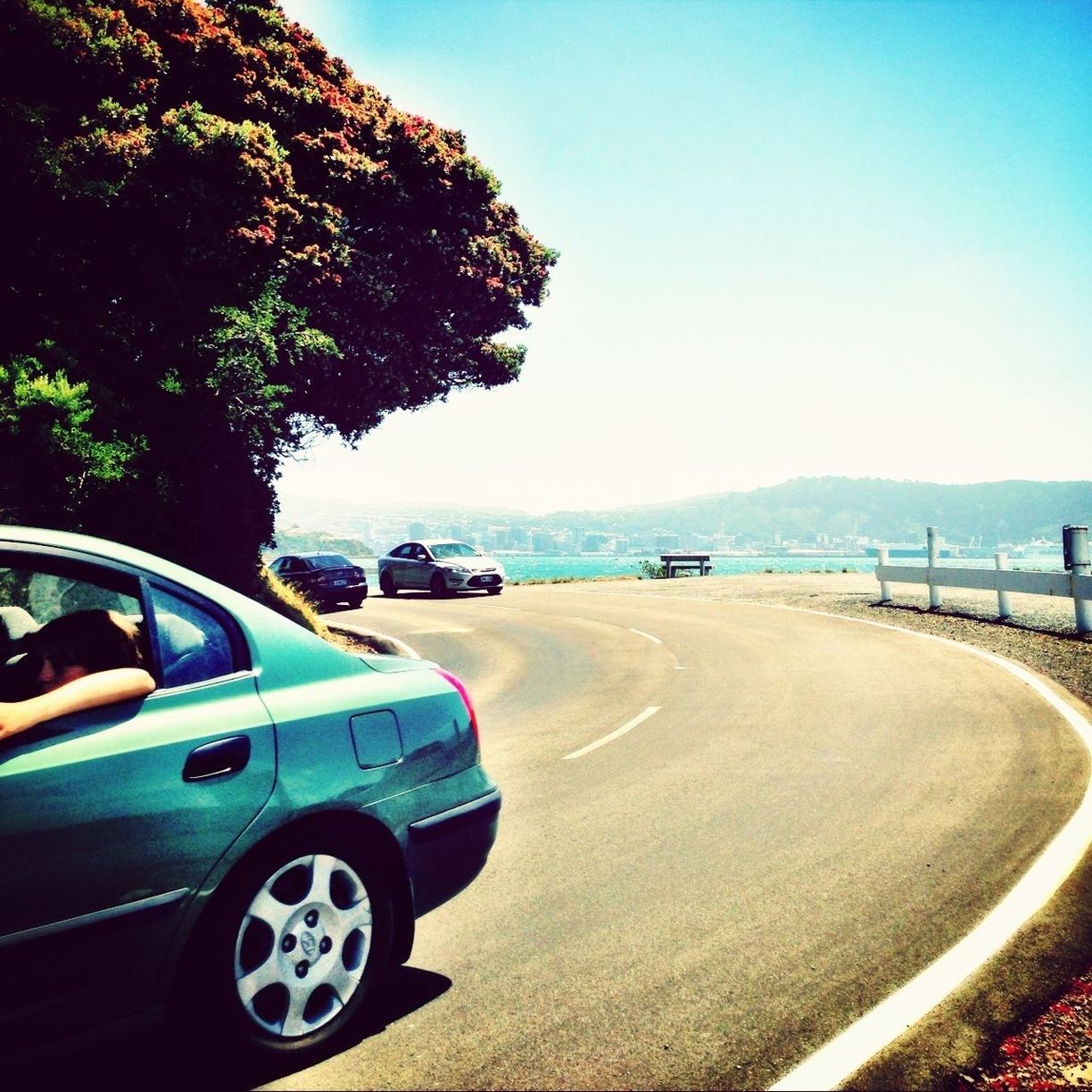 transportation, clear sky, road, mode of transport, land vehicle, car, blue, tree, road marking, copy space, sunlight, travel, sky, tranquility, tranquil scene, day, beach, nature, sea, street