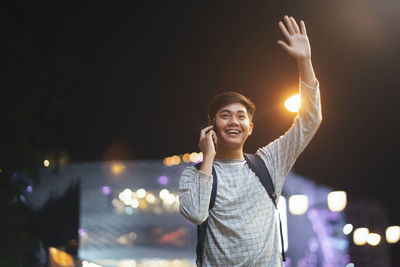Smiling woman standing against illuminated city at night