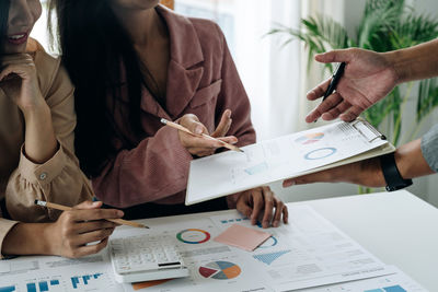 Midsection of business colleagues working on table