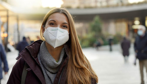 Close up of confident woman wearing medical mask in city street as prevention against virus