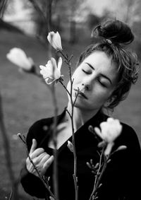 Woman with eyes closed standing by flowers