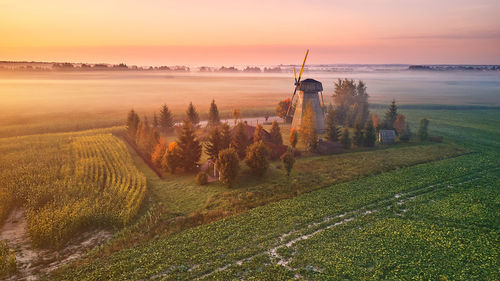 Traditional wooden windmill morning landscape. rural colorful sunrise, foggy green fields. dudutki 