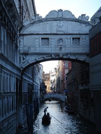 Man on gondola below bridge of sighs at grand canal in city