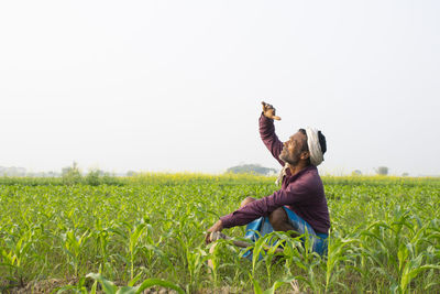 Full length of man with arms raised on field against clear sky