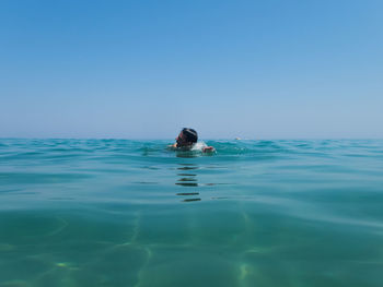 Man swimming in sea against clear sky