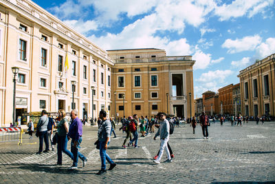 People on street against buildings in city