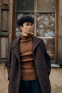 Portrait of young woman standing against wall