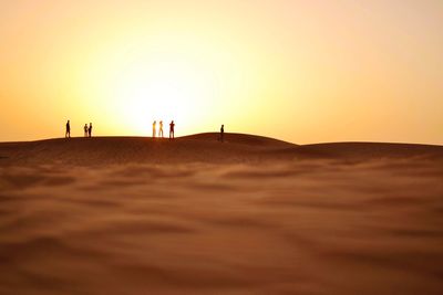 Silhouette people on beach against sky during sunset