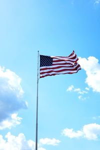 Low angle view of flag waving against blue sky