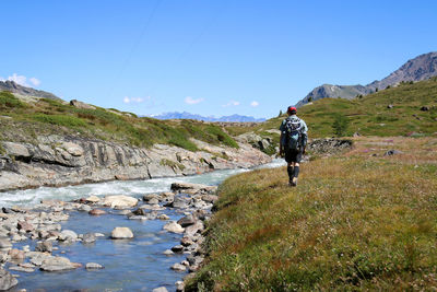 Rear view of man standing on mountain against sky