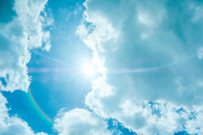 Low angle view of sunlight streaming through clouds