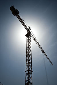 Low angle view of crane at construction site against sky