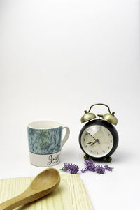 Close-up of clock on table against white background