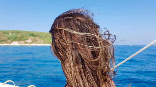 Rear view of woman against blue sea