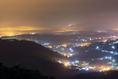 Illuminated city against sky at night