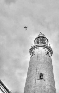 A plane passes over a lighthouse