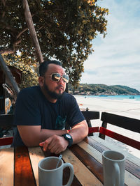 Portrait of young man sitting at beach