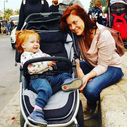 Happy redhead woman by daughter sitting on baby stroller