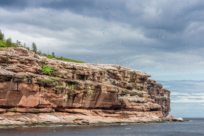 Rock formations by sea against sky