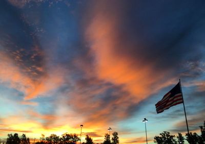 Low angle view of flag against orange sky