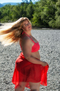 Beautiful young woman standing against red water