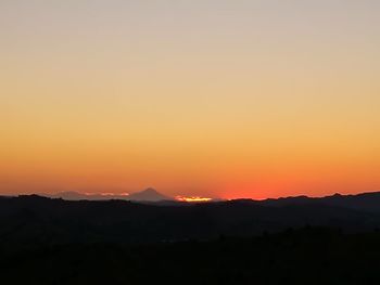Scenic view of silhouette mountains against romantic sky at sunset