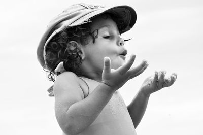 Close-up of shirtless girl playing against sky