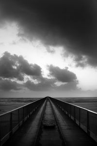 Pier leading towards sea against sky