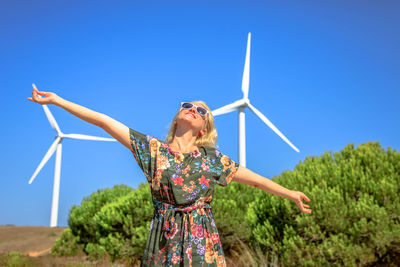 Woman with arms outstretched standing on land against sky