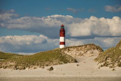 Lighthouse by street amidst buildings against sky