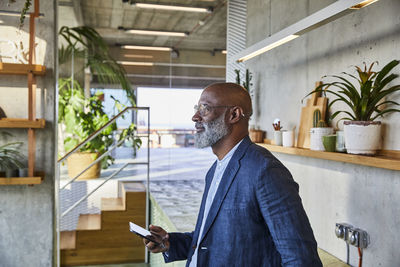 Man looking away while using smart phone at home