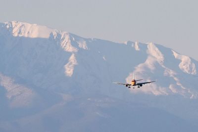 Low angle view of airplane flying against snowcapped mountains