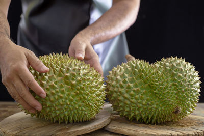 Midsection of man holding fruit on table