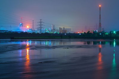 Illuminated bridge over river against sky at night