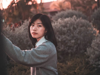 Portrait of young woman standing against plants