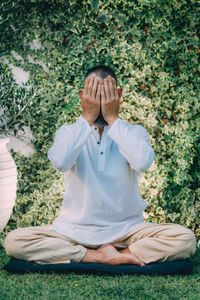 A man sitting with his eyes closed and doing reiki self-treatment