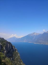 Scenic view of sea and mountains against clear blue sky