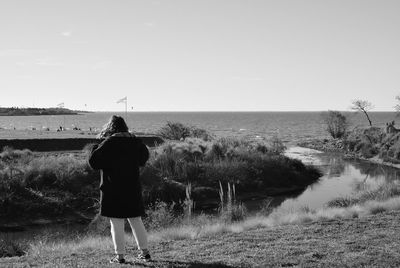 Rear view of woman looking at sea against clear sky