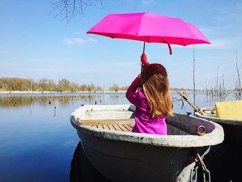 Rear view of girl holding umbrella while sitting in boat