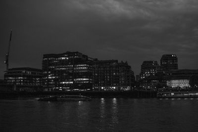 Buildings by river against sky