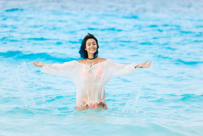 Portrait of smiling young woman standing in sea