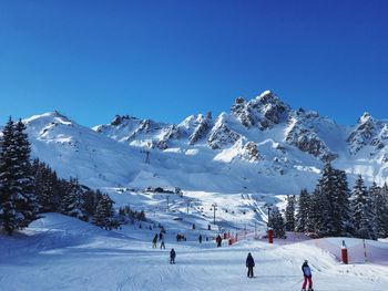 Scenic view of snow covered mountains against clear blue sky