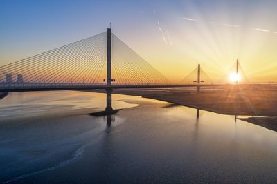 View of suspension bridge against sky during sunrise 