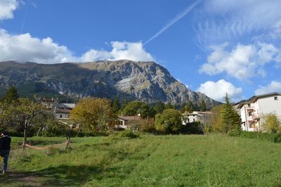 Houses on field by mountain against sky