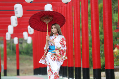 Full length of woman holding red umbrella